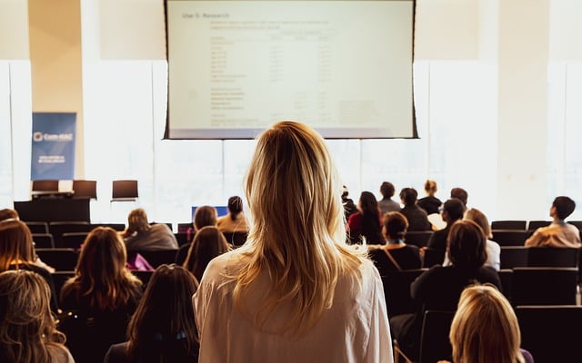 Eventos corporativos: mulher observa tela e participantes 