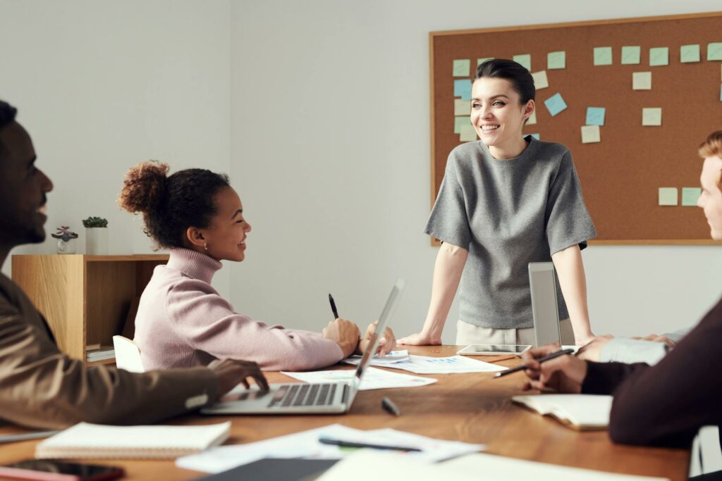 Reunião de equipe liderada por uma profissional sorridente, exemplificando soft skills para liderança, como escuta ativa e trabalho em equipe, fundamentais entre 10 exemplos de soft skills mais valorizados no mercado.