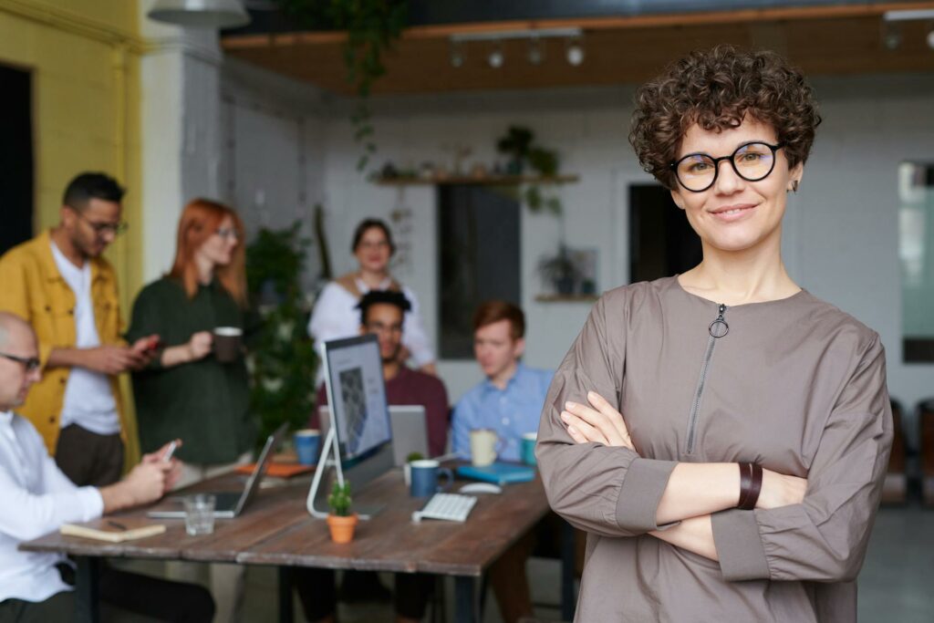 Líder em destaque com sua equipe colaborativa ao fundo, ilustrando o significado de soft skills para liderança, como comunicação e empatia, para um ambiente de trabalho eficaz e liderança inspiradora.