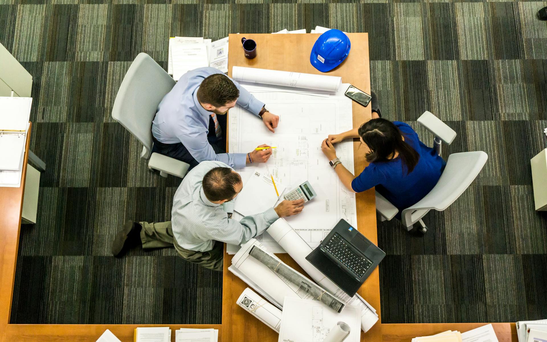 Visão superior de equipe sentada à mesa com papéis mostrando projeto representa as 5 melhores empresas de gamificação, com destaque para a PlayerUm.